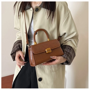Bolso bandolera de cuero marrón retro con cierre dorado combinado con un abrigo beige
