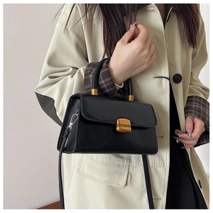 Detalle de bolso vintage de cuero encerado negro con hebilla dorada y diseño cuadrado