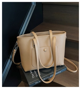 Detail of camel lychee texture tote bag with front pocket on a book display