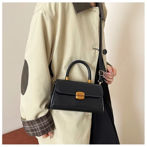 Detalle del bolso cuadrado negro de cuero encerado vintage con asa dorada y cierre