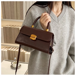 Bolso bandolera chic de cuero encerado marrón oscuro con un jersey de punto gris elegante