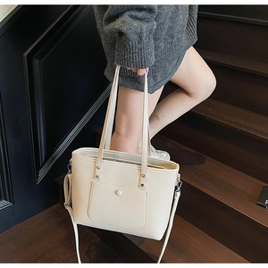 Detail view of a beige pebbled leather tote bag with functional front flap pocket
