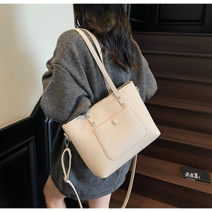Detailed back view of a creamy white pebbled leather tote bag worn as a shoulder bag