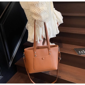 Close-up of brown lychee texture tote bag with silver buckle on wooden stairs