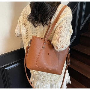 Detail of brown litchi pattern leather tote bag with dual straps and front pocket