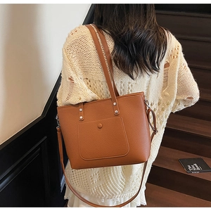 Brown lychee texture tote bag with buckle pocket shown in a lifestyle shoulder carry view
