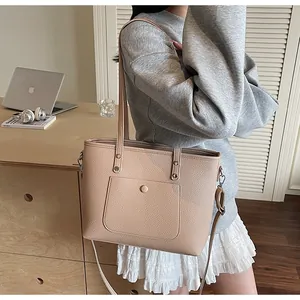 Detail view of beige lychee texture tote bag with snap pocket on office desk background