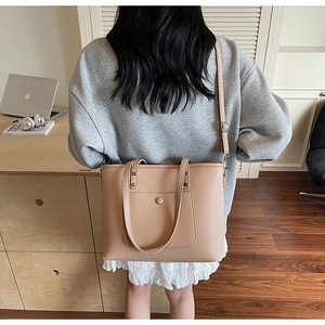 Beige pebble leather tote bag shown with model in a home office setting on shoulder