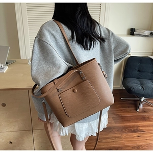 Close-up of brown pebbled leather tote bag featuring a front pocket and adjustable strap