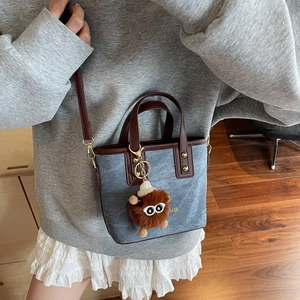 Retro denim canvas mini bucket bag with brown leather handles and plush charm accessory