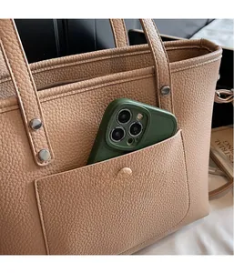 Detailansicht der braunen Ledershopper-Tasche mit Außentasche und einem Smartphone darin