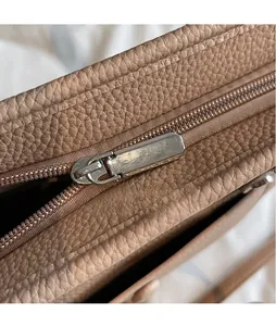 Nahaufnahme der genarbten Lederstruktur und poliertem Silberreißverschluss am Tasche