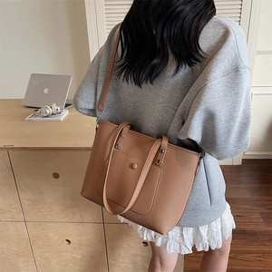 Brown large capacity leather tote bag with shoulder strap shown in a home office scene