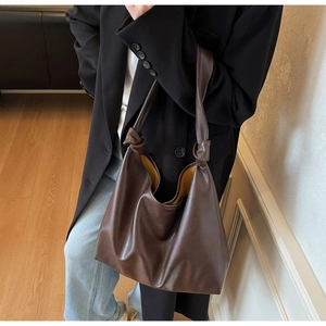 Detail of soft brown leather tote with knot strap and contrasting yellow lining
