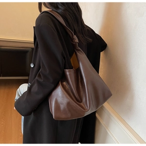 Close-up of deep brown leather tote bag featuring unique knot detail on the shoulder strap