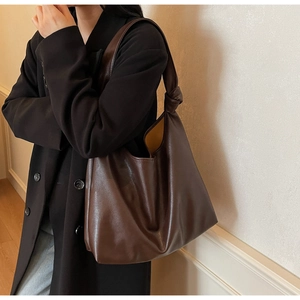 Detail of soft brown tote bag featuring unique shoulder strap knot and contrast lining
