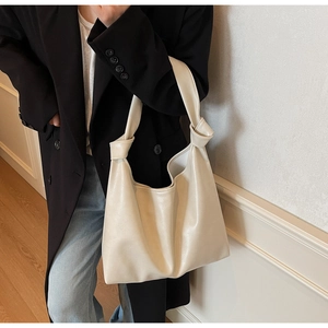 Chic cream-white knotted hobo shoulder bag styled with a minimalist black blazer