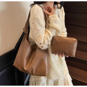 Brown knot shoulder bag and matching pouch shown on a model against wooden stairs