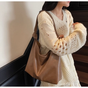 Brown soft PU leather hobo bag with knotted strap detail shown on a model