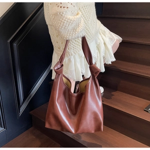 Detail of trendy brown knotted handle tote bag showing high-quality matte leather texture