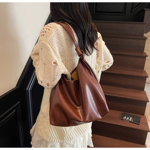 Close-up of brown PU leather tote bag with knotted shoulder strap and pleated detailing