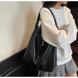 Side view of a large black faux leather hobo shoulder bag styled on a female model