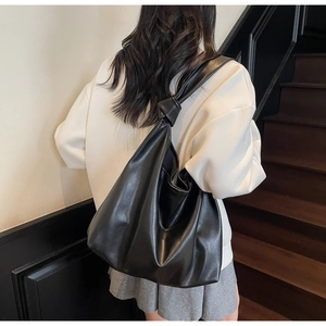 Detail of black PU leather hobo tote showing knotted shoulder strap and soft texture