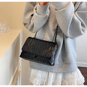 Detail of black quilted leather shoulder bag with chain strap and oval ring buckle