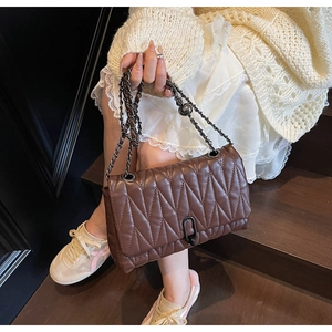 Macro detail of brown quilted leather bag with gunmetal chain and black ring clasp