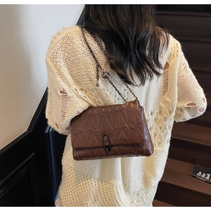 Model view of dark brown quilted crossbody bag with metal chain and V-pattern stitching