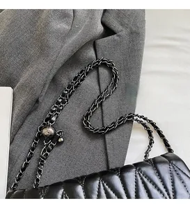 Close-up of black quilted leather bag with V-shaped stitching and metallic chain strap