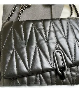 Detailed close-up of black V-quilted leather texture and matte metal oval buckle