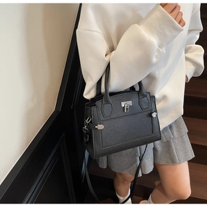 Detailed view of black litchi pattern leather handbag with silver twist lock and handle