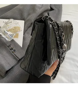 Detail of black quilted leather bag featuring a gunmetal chain and star sphere charm