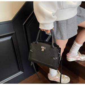 Action shot of a large black litchi grain leather handbag with silver hardware details
