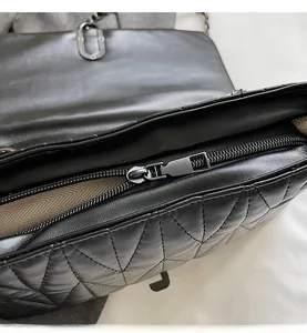Close-up of smooth metal zipper and herringbone fabric lining on a quilted bag