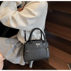 Close-up of black lychee grain handbag featuring silver clasp and detachable strap