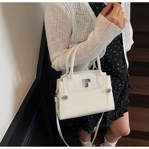 Detailed view of white lychee grain handbag with silver buckle worn on a shoulder