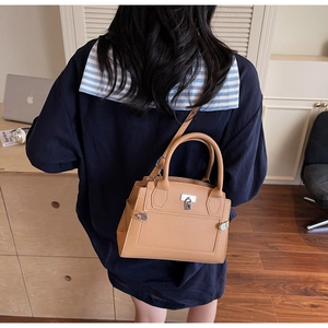 Light brown pebble leather handbag with silver lock shown worn by a model in casual style