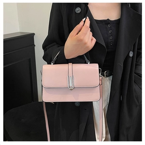 Close-up of pink leather handbag with silver metal clasp on black trench coat outfit