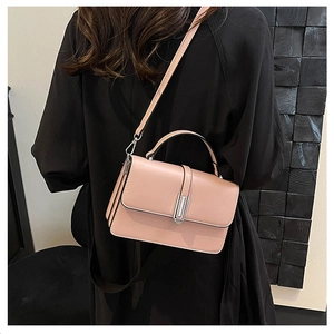 Detail of light pink leather handbag with silver metallic buckle on a model's shoulder