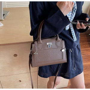 Detail of dark brown lychee leather handbag with silver twist lock and side strap design