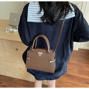 Brown lychee leather tote bag shown cross-body in a modern office workplace setting