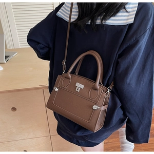 Close-up of brown litchi pattern leather bag with silver metal buckle on a shoulder strap