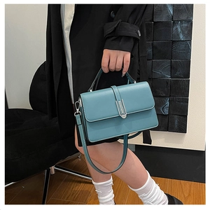Detail shot of cyan minimalist handbag with white stitching and silver metal buckle