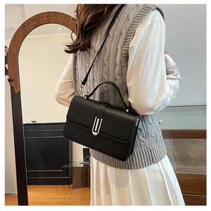 Detail of black crossbody bag with silver U-shaped metal buckle and slim leather strap