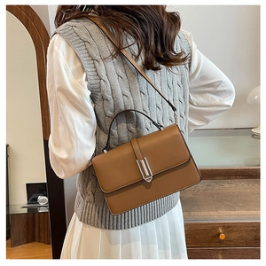 Brown leather crossbody bag detail with silver buckle and model's outfit matching