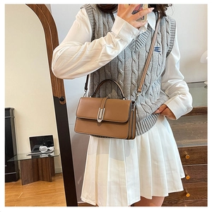 Brown rectangular handbag featuring a silver buckle and crossbody strap on a lifestyle model