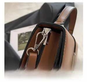 Macro shot of silver metal hooks and black reinforced edges on brown leather shoulder bag