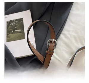 Detail of adjustable brown leather shoulder strap with silver buckle on a women bag